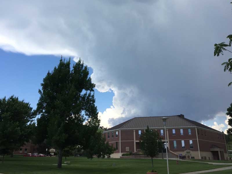 Campus building with natural landscape of trees and sky.