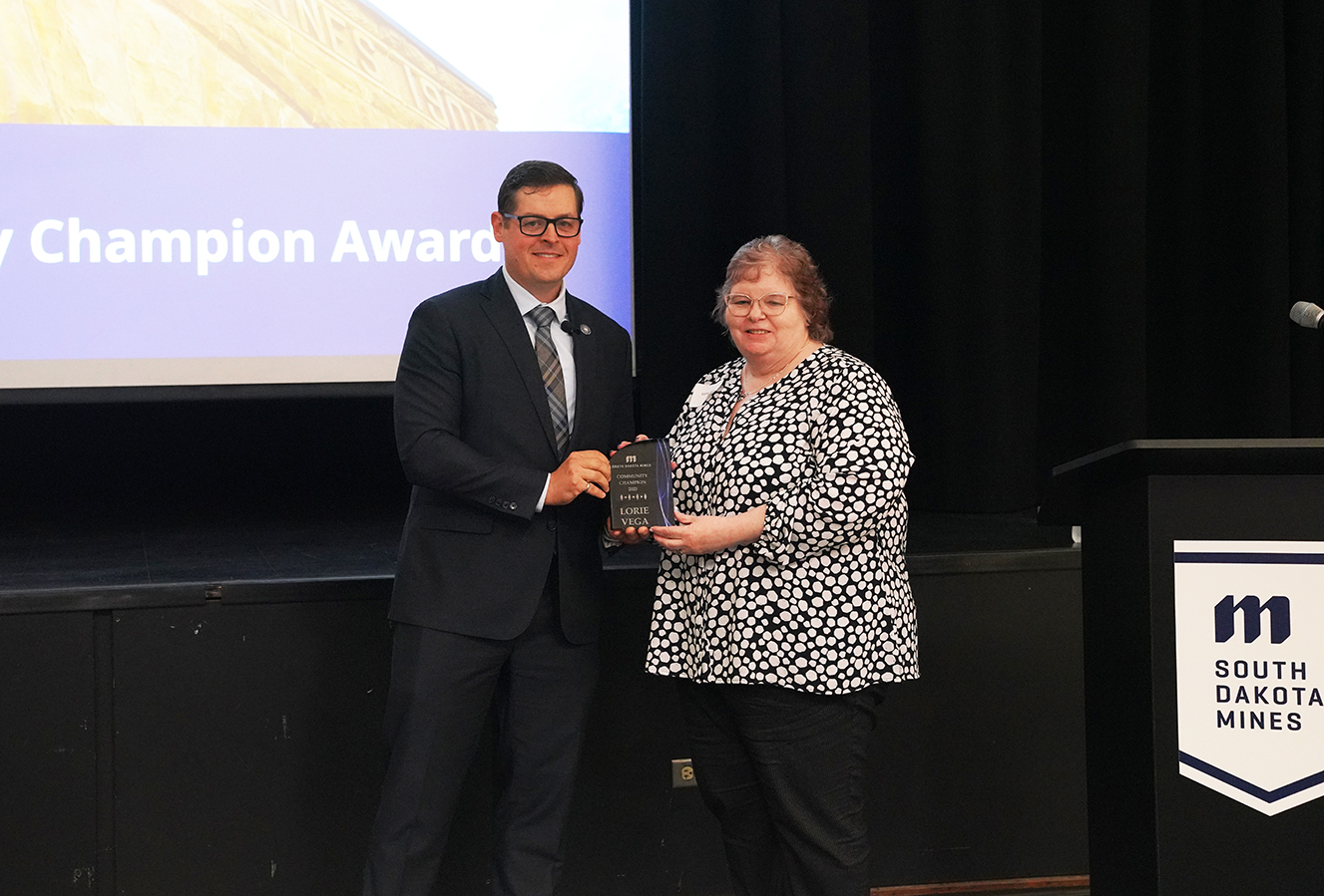 Dr. Brian Tande presents Lorie Vega, the deputy for the 28th Mission Support Group at Ellsworth Air Force Base, as a 2025 Community Champion.